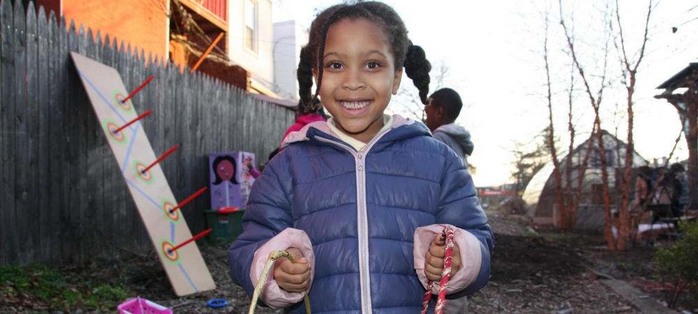 A young girl smiling and holding a present at the Annual Christmas Celebration