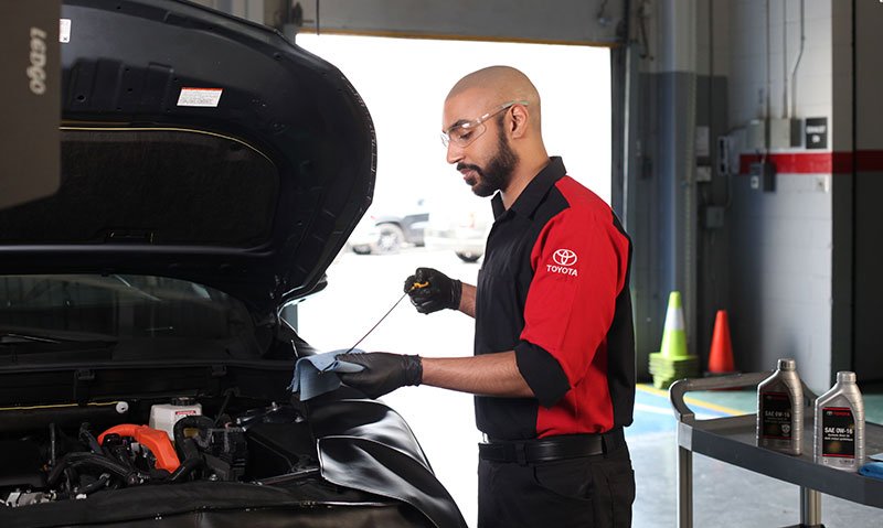 A Toyota Certified Technician checking the fluid levels of a Toyota vehicle