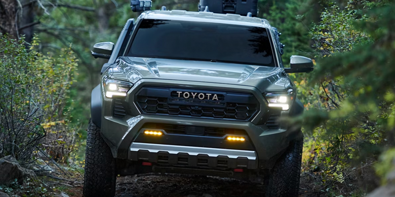 A Toyota truck driving off-road through a forested area